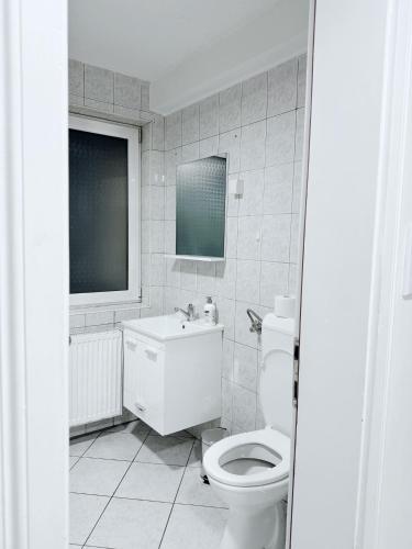 a white bathroom with a toilet and a sink at Modern Lux Apartment in Brčko