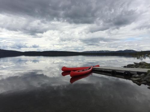 a couple of red canoes sitting on a dock on a lake at Rondane Høyfjellshotell in Mysusæter