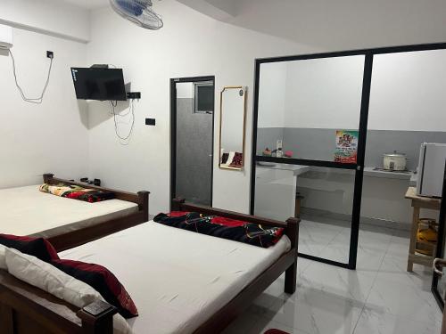 two beds in a room with a mirror and a tv at David Villa in Anuradhapura