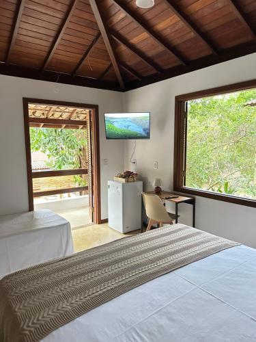 une chambre avec un lit, un bureau et une télévision dans l'établissement Pousada ViniCarmel Arraial d ajuda, à Arraial d'Ajuda
