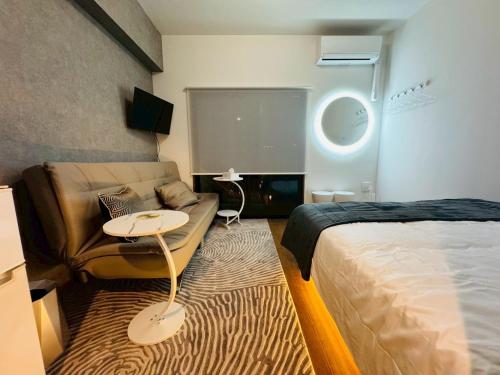 a room with a bed and a couch and a table at LuxurySweet 博多駅南63 in Fukuoka