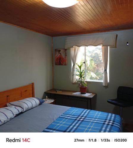 a bedroom with a bed and a desk and a window at Alojamiento Monitor Huáscar in Talcahuano