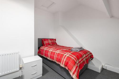 a bed with a red plaid blanket in a room at Immingham Contractors stay in Immingham