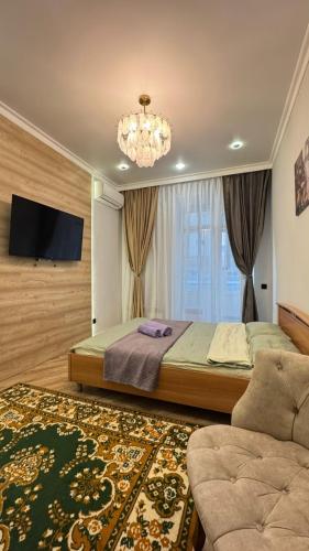 ein Schlafzimmer mit einem Bett, einem Fernseher und einer Couch in der Unterkunft Квартира на левом берегу в ЖК Alpamys A4 in Astana