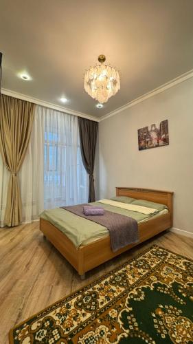 ein Schlafzimmer mit einem großen Bett und einem Kronleuchter in der Unterkunft Квартира на левом берегу в ЖК Alpamys A4 in Astana