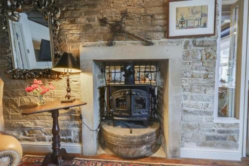 a stone fireplace with a stove in a room at Canal Cottage Rodley Leeds, 5 miles LBA Airport in Leeds