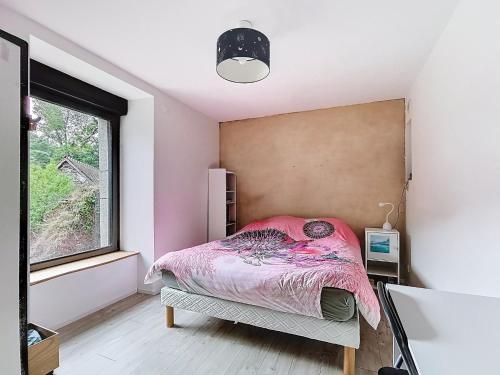 1 dormitorio con cama rosa y ventana en Le Moulin Hochet, en Les Pieux