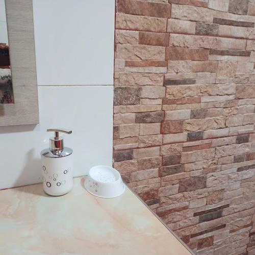 une salle de bain avec un mur de briques et un lavabo dans l'établissement Comfortable departamento de 2 habitacones en la Victoria con garaje gratis, à Ibarra