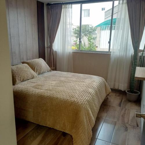 une chambre avec un lit et une grande fenêtre dans l'établissement Comfortable departamento de 2 habitacones en la Victoria con garaje gratis, à Ibarra