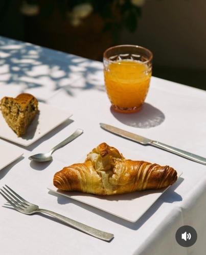 Giardino Principi Dafagi Suite Luxury con Jacuzzi & parcheggio في Capurso: طاولة مع صحن من الخبز وكوب من عصير البرتقال