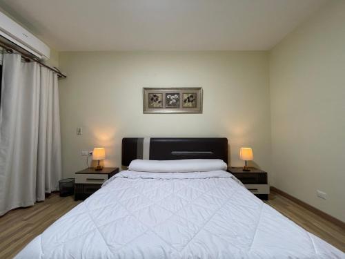 a bedroom with a large bed with two lamps on tables at Modern apartment with garden in Sheikh Zayed
