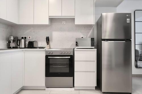 a kitchen with white cabinets and a stainless steel refrigerator at Skyline Views at Madinat Jumeirah Living in Dubai