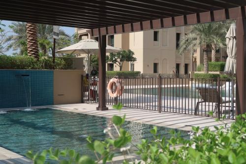 a swimming pool with an umbrella and a table and chairs at Skyline Views at Madinat Jumeirah Living in Dubai