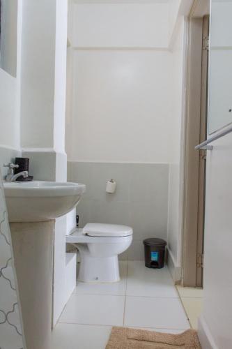 a white bathroom with a toilet and a sink at Duplex 1BR Apartment along Waiyaki Way, Nairobi in Nairobi