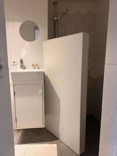 a white bathroom with a sink and a shower at Cozy tiny house close to Schiphol Ams Airport in Rijsenhout