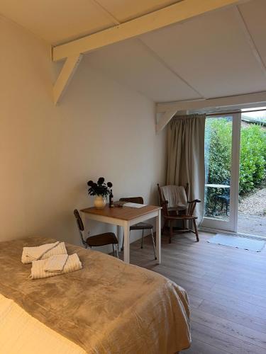 a bedroom with a bed and a table and chairs at Cozy tiny house close to Schiphol Ams Airport in Rijsenhout