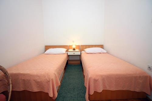 2 Betten in einem kleinen Zimmer mit einem Nachttisch dazwischen in der Unterkunft Apartman Mravinac in Tisno