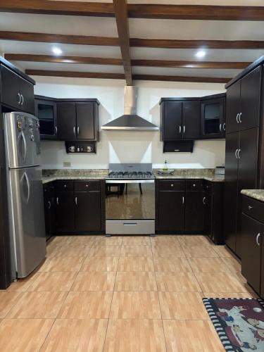 a kitchen with black cabinets and stainless steel appliances at Casa acogedora cerca de la playa in Ensenada