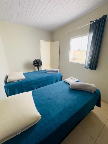 two beds in a room with blue sheets and a window at Flat Vila Mariana in Tianguá