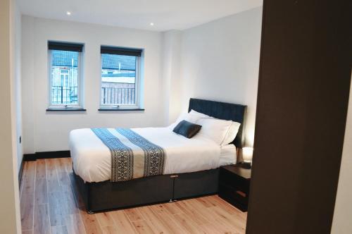 Un dormitorio con una cama y dos ventanas en Elegant 2 bed flat with balcony in London, en Finchley
