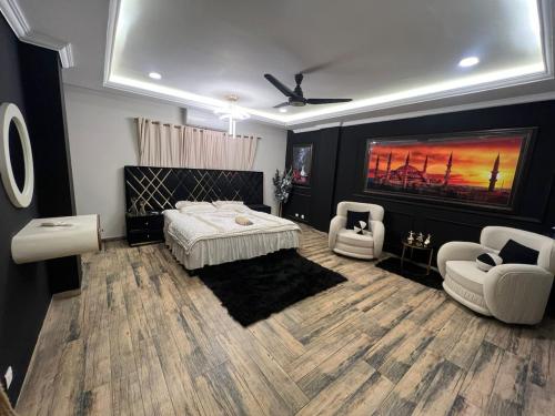 ein Schlafzimmer mit einem Bett und zwei Stühlen darin in der Unterkunft Modern 2BHK ApartmentPool Netflix in Rawalpindi