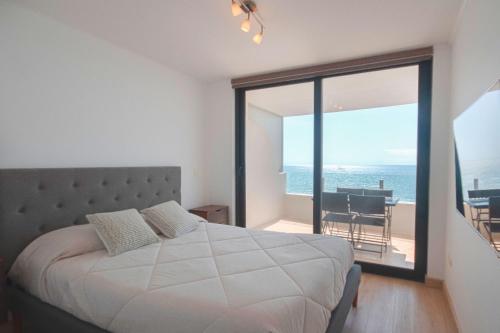 ein Schlafzimmer mit Bett und Blick auf das Meer in der Unterkunft Oceanic relájate cerca de todo in La Serena