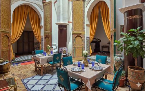 a dining room with two tables and blue chairs at Riad Zina Fes - Elegance in the Heart of Fes in Fès
