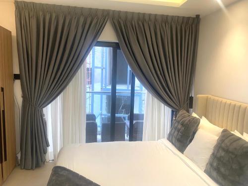 ein Schlafzimmer mit einem Bett und einem großen Fenster in der Unterkunft Belrose Place in Accra