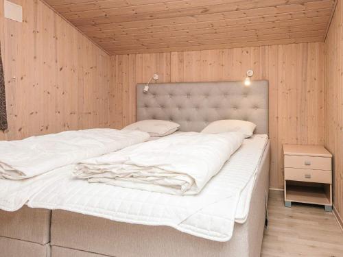 a large white bed in a room with wooden walls at 6 person holiday home in Oksbøl-By Traum in Oksbøl