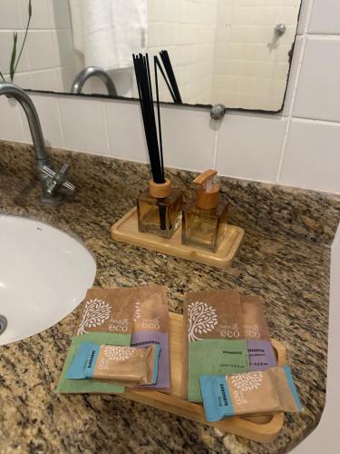 un plateau en bois avec des baguettes sur un comptoir de salle de bain dans l'établissement Pousada ViniCarmel Arraial d ajuda, à Arraial d'Ajuda