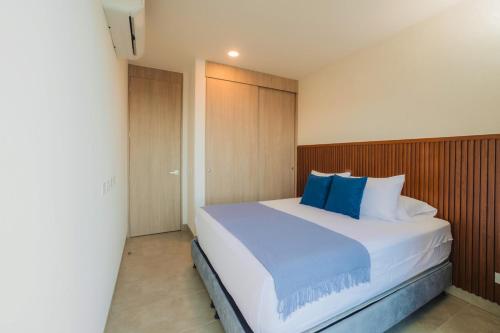 Apartment on the 21st floor, ocean and Sierra views في Simón Bolivar: غرفة نوم بسرير أبيض كبير مع وسائد زرقاء