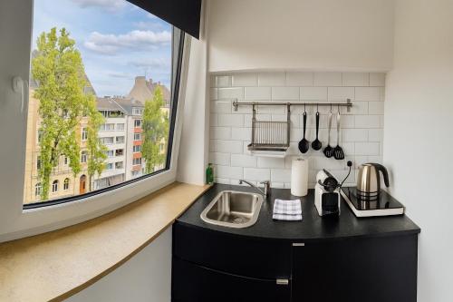 een keuken met een wastafel en een groot raam bij Apartments KR in Keulen