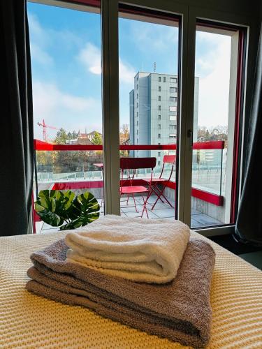 a pile of towels sitting on a bed in front of a window at Modern Living, Luxe Apartment Zurich in Zurich
