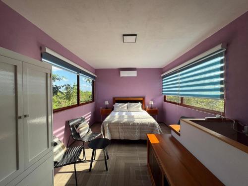 a bedroom with purple walls and a bed and a window at Casa en Huerto Frutal in Chicanna