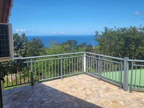 a balcony with a view of the ocean at Chambre indépendante calme pour femmes, en forêt, 1km plage in Deshaies