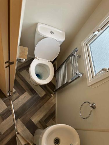 a small bathroom with a toilet and a window at 3 bedroom 8 berth Standard Basic caravans with Hot Tub,Mountain Bikes in Tattershall