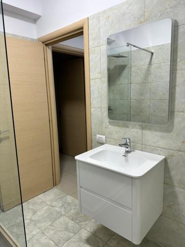 een badkamer met een witte wastafel en een spiegel bij Premium Apartments Tirana Cumani in Tirane