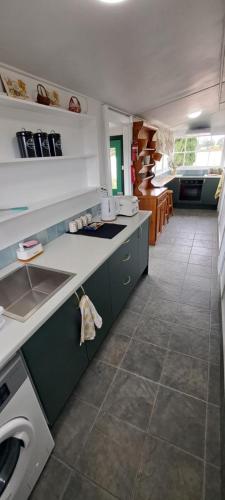 a kitchen with a sink and a washing machine at Heartland cottage in Ross