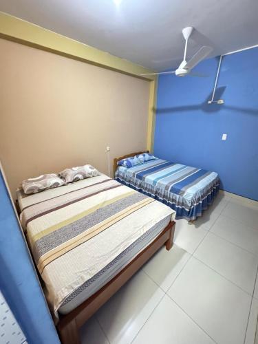 two beds in a room with blue walls at Hospedaje obsesión in Pucallpa