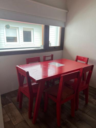 a red dining room table with red chairs and a window at Chalten Mountain Loft 8 in El Chalten
