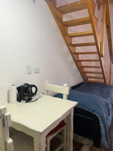 a room with a bed and a table with a stairs at Chalten Mountain Loft 8 in El Chalten