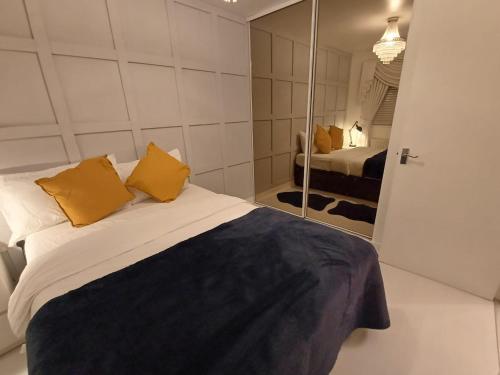 a bedroom with a bed with yellow pillows and a mirror at Luxury 3 Bedroom House with Parking in Northfleet