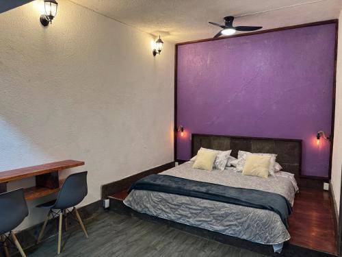 ein Schlafzimmer mit einem Bett und einer lila Wand in der Unterkunft HaciendaBosque in Cuernavaca