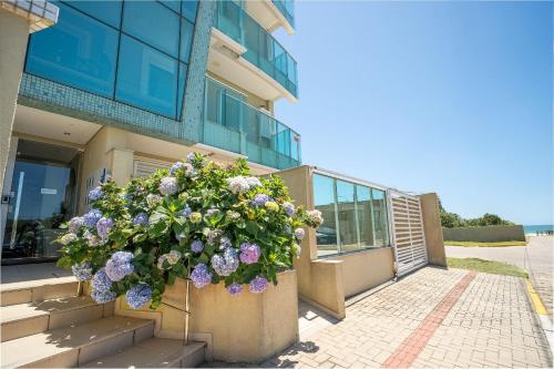 a planter filled with flowers in front of a building at Apartamento vista para o mar com 02 dormitórios in Canto Grande