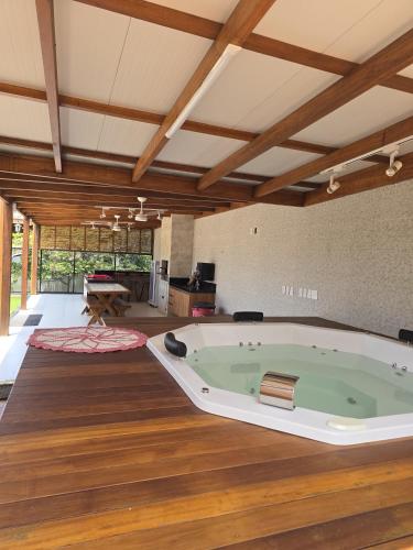 a jacuzzi tub in a room with wooden floors at Casa de alto padrão com piscina,quadra e jacuzzi em condomínio in Guarapari