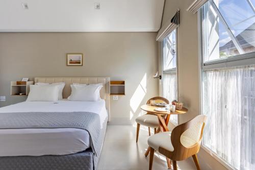 a bedroom with a bed and a table and chairs at Vilinha típica - Suíte Onze Tuin - Entrada com senha - Somos hospedagem por temporada in Holambra