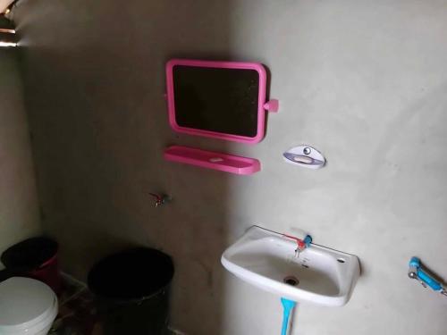 une salle de bain avec un lavabo et une télévision au mur dans l'établissement Homestay Nunga หนูหง่าโฮมสเตย์คุณครู, à Mae Hong Son