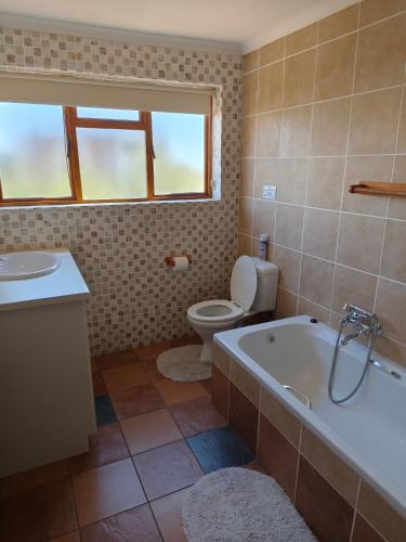 a bathroom with a tub and a toilet and a sink at Net Net Holiday Home in Witsand