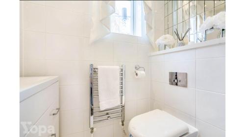 a white bathroom with a toilet and a window at Luxury 3 Bedroom House with Parking in Northfleet