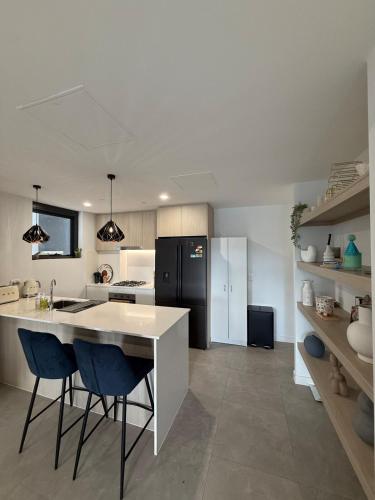 a kitchen with a white counter and a black refrigerator at The Gosford Modern Nest in Gosford